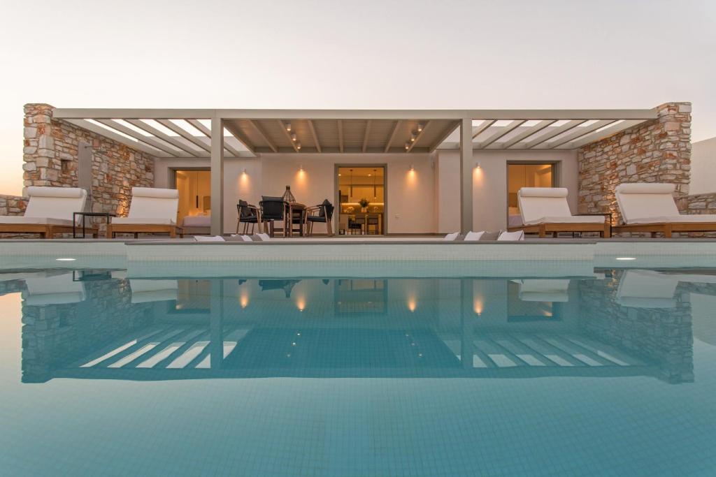 una piscina con sillas y una casa en T7 LUXURY VILLAS PAROS en Kampos Paros