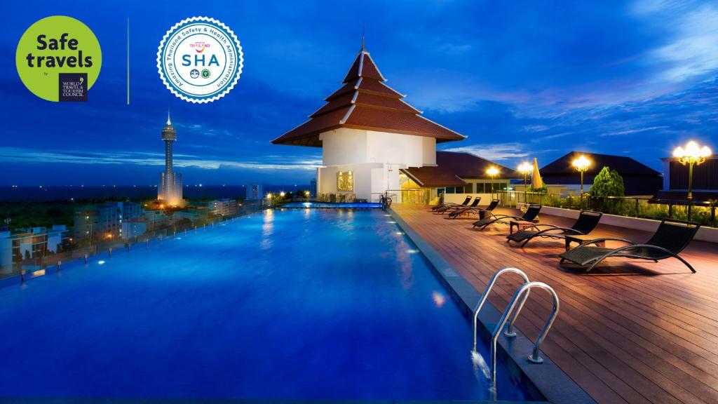 ein Hotelpool in der Nacht mit einem Turm im Hintergrund in der Unterkunft Aiyara Grand Hotel in Pattaya South