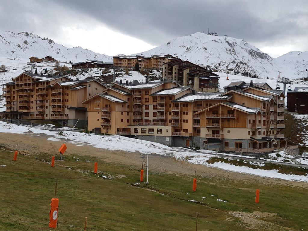 ein großes Gebäude mit schneebedeckten Bergen im Hintergrund in der Unterkunft Appartement Plagne Soleil, 2 pièces, 5 personnes - FR-1-351-89 in Plagne Villages