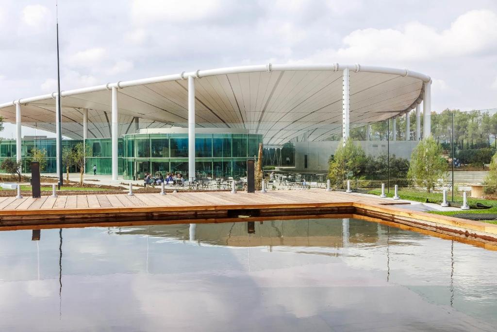 a large building with a wooden deck in front of a body of water at thecamp hôtel Eco Lodge- Aix en Provence in Aix-en-Provence