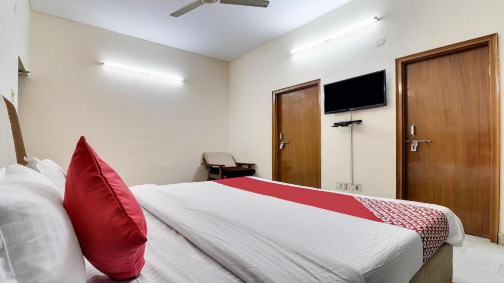a bedroom with a bed with red pillows and a flat screen tv at ANH Hotel in Lucknow
