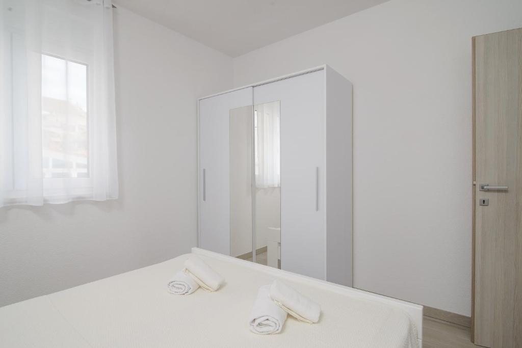 biała łazienka z umywalką i lustrem w obiekcie Apartmani Manuela w Okrugu Gornjim