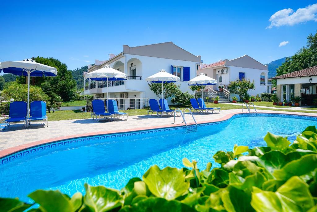 una piscina con sillas y sombrillas frente a una casa en Antigone Hotel, en Limenas