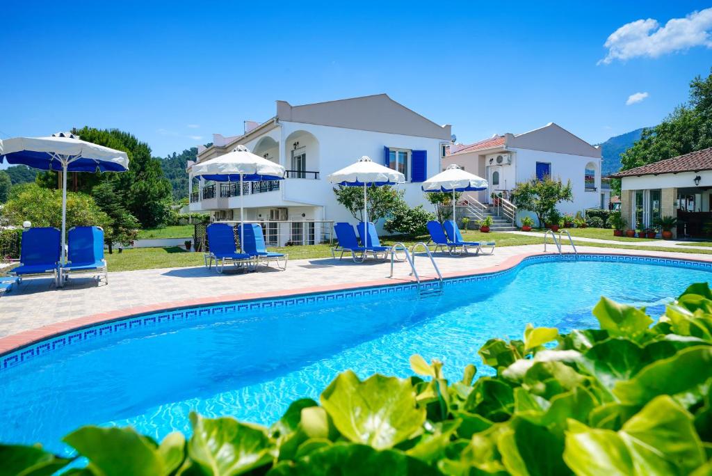 a swimming pool with chairs and umbrellas in front of a house at Antigone Thassos Hotel in Limenas