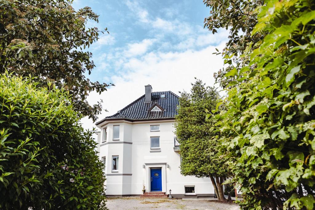 uma casa branca com uma porta azul e árvores em DAS STRANDGLÜCK - Villa und Mee(h)r em Graal-Müritz