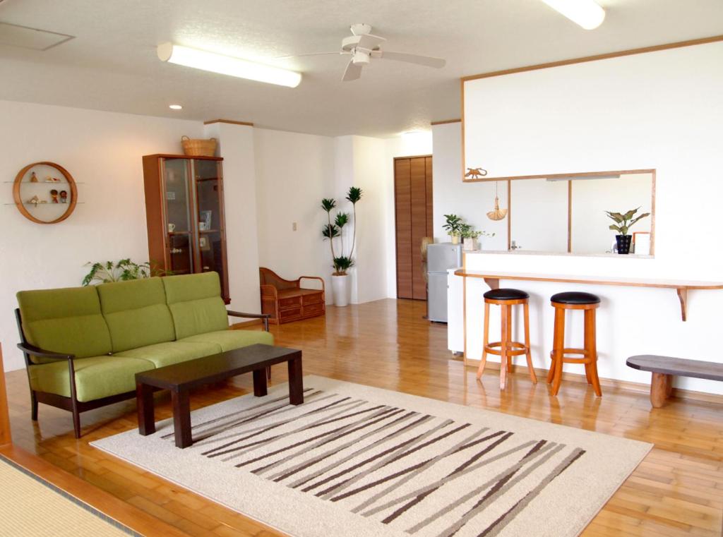 a living room with a green couch and a kitchen at Rental Villa Luana Waioli in Tomigusuku