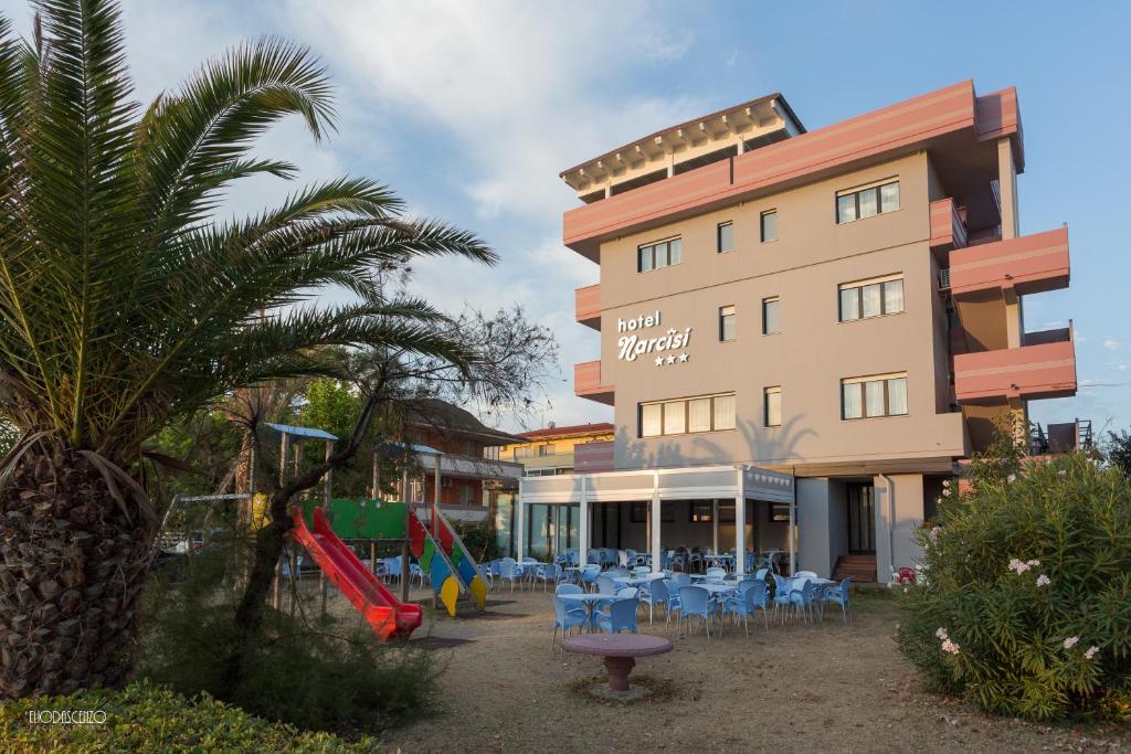 um hotel com mesas e cadeiras em frente a um edifício em HOTEL NARCISi2 em Roseto degli Abruzzi