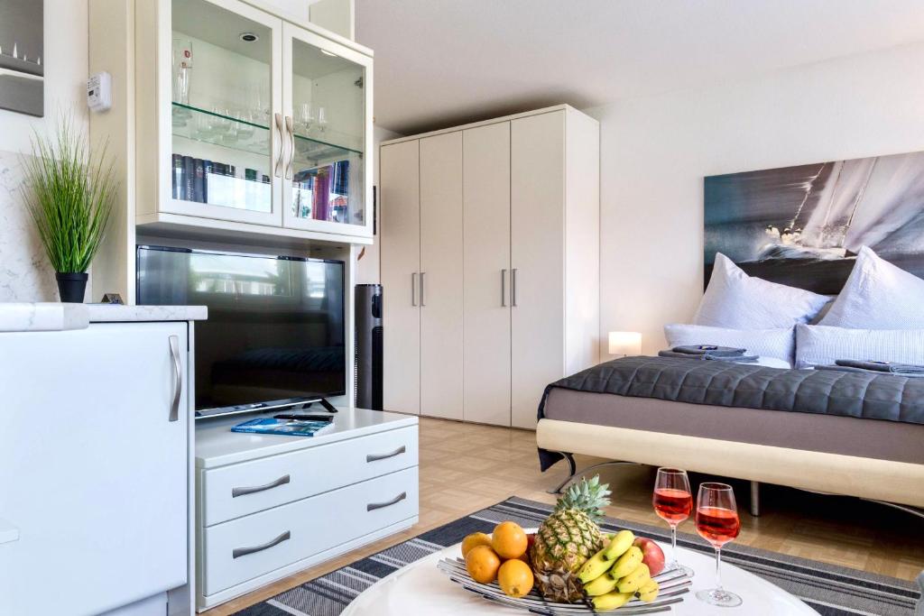 ein Schlafzimmer mit einem Bett und einem Tisch mit Obst und Weingläsern in der Unterkunft Auszeit Apartment DOWNTOWN im Herzen der Innenstadt - am Hafen und am Bodenseeradweg - schnelles Internet, für bis zu 2 Personen in Friedrichshafen
