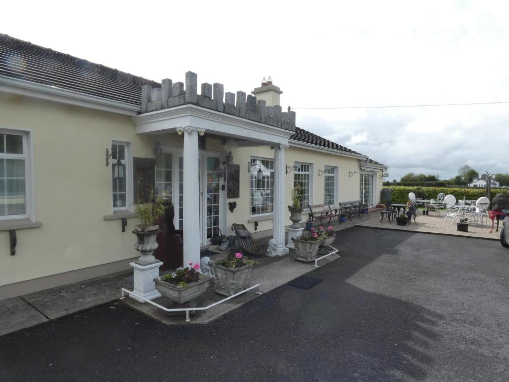 une maison blanche avec une terrasse couverte ornée de plantes en pot dans l'établissement Bunratty Castle Mews B&B, à Bunratty