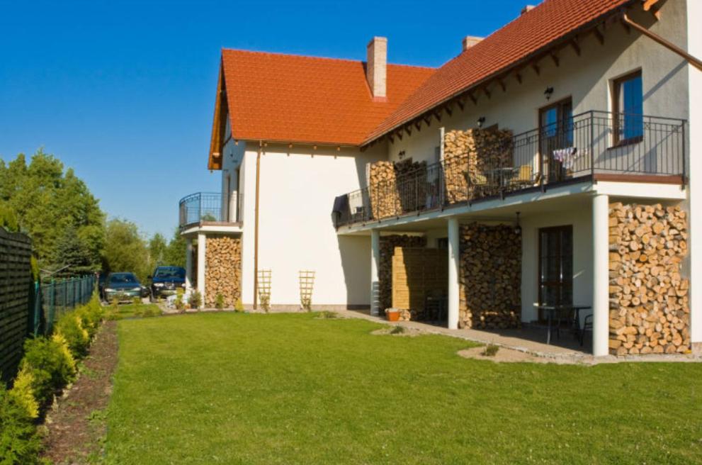 una casa con un césped verde delante de ella en Apartamenty na Wydmie, en Gąski