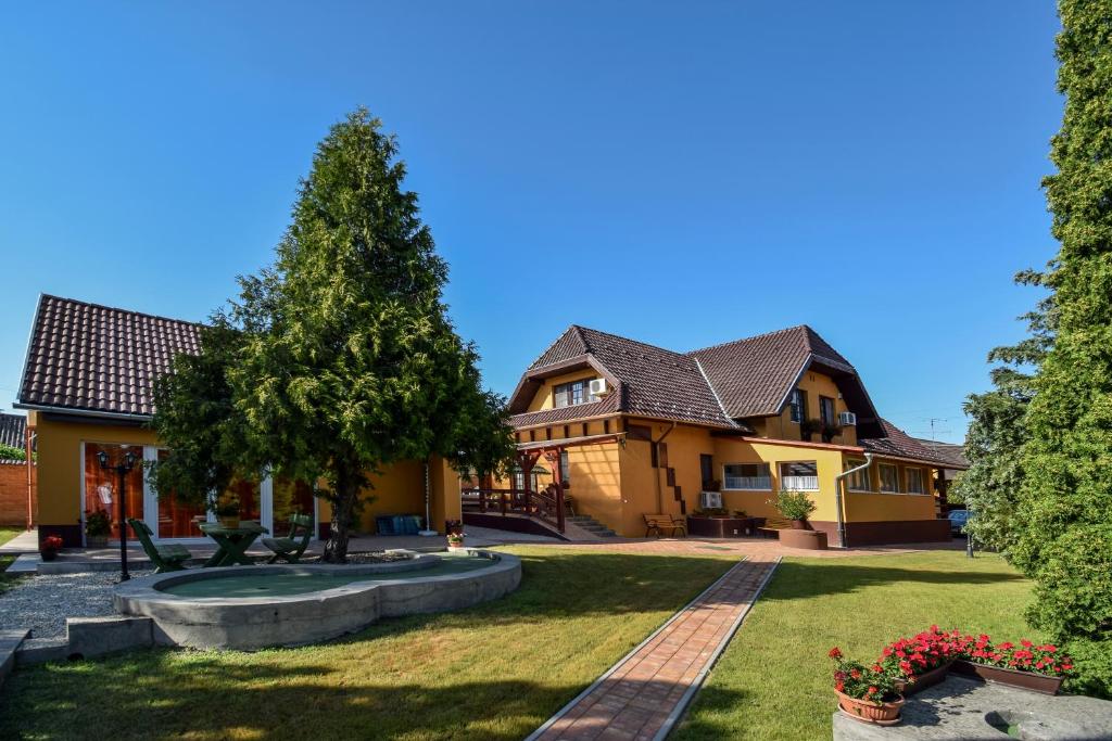 una casa grande con un patio con un árbol en Gála Panzió, en Simontornya