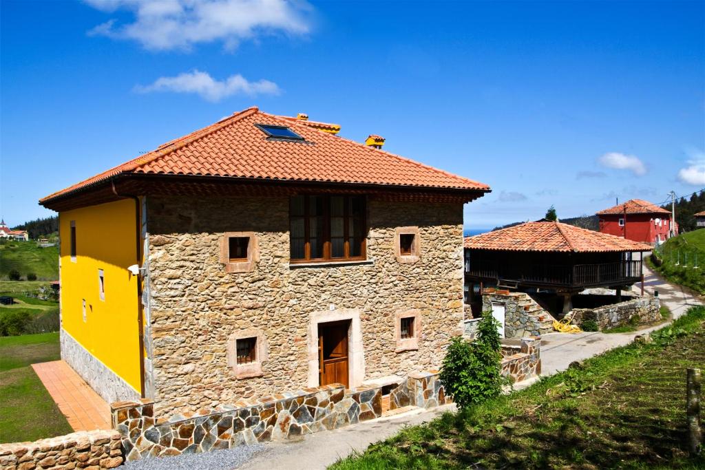a stone building with a red roof on a hill at Casa Rural Los Sombredales in Soto del Barco