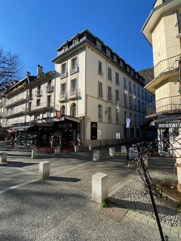un grand bâtiment blanc dans une rue de la ville dans l'établissement Bagnères de Luchon, Résidence Val de Jade, Beau T3 meublé, plein centre, pour 4 ou 6 personnes, à Luchon