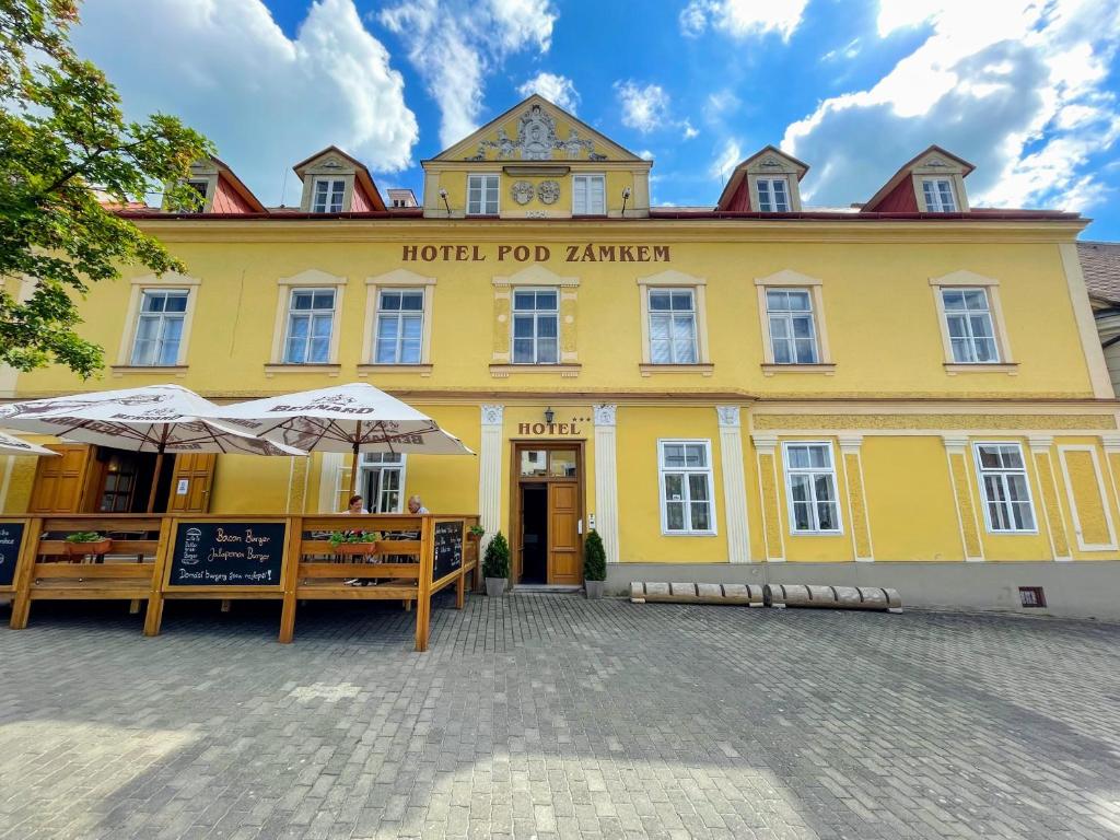 ein gelbes Gebäude mit Sonnenschirmen davor in der Unterkunft Hotel Pod Zámkem in Vranov nad Dyjí