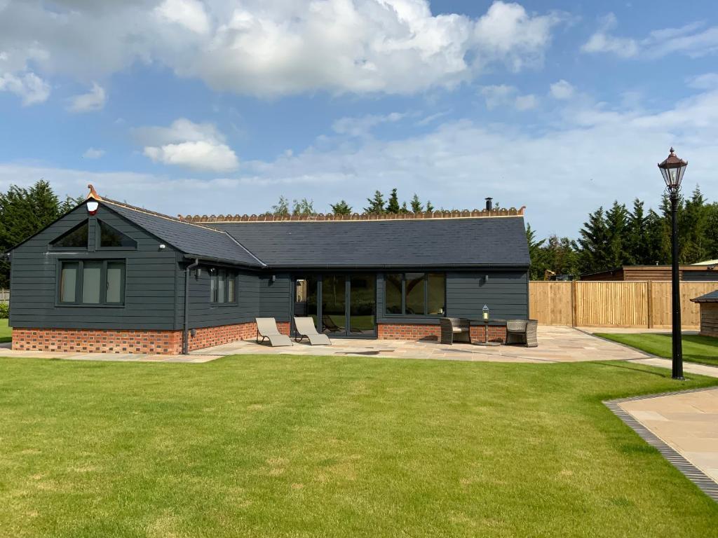 a gray house with a lawn in front of it at Little Oak Lodge in Hailsham