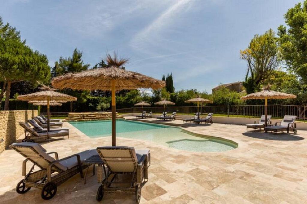 a swimming pool with chairs and umbrellas at La Bastide de l Etang in LʼIsle-sur-la-Sorgue