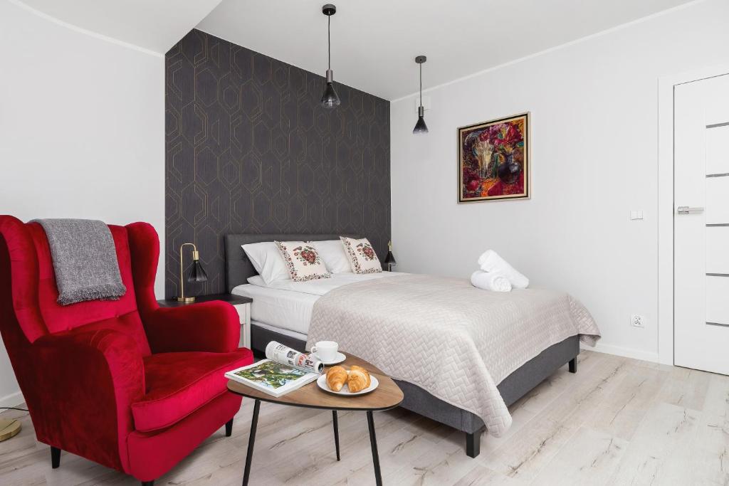 a bedroom with a bed and a red chair at Stara Polana Apartamenty & Spa Zakopane by Renters Prestige in Zakopane