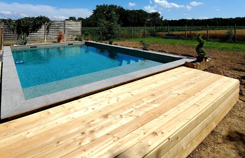 een zwembad in een tuin met een houten terras bij Maison villa de charme in Saasenheim