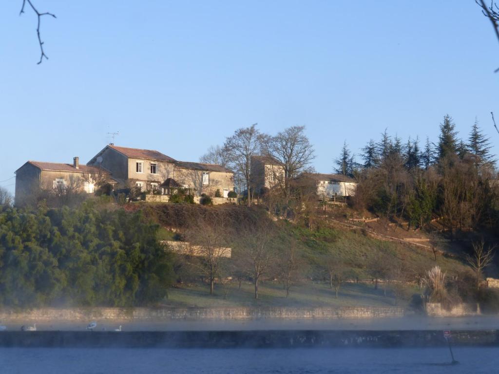 Grande maison escapade au bord de la riviere في Touvre: منزل على قمة تل بجوار بحيرة