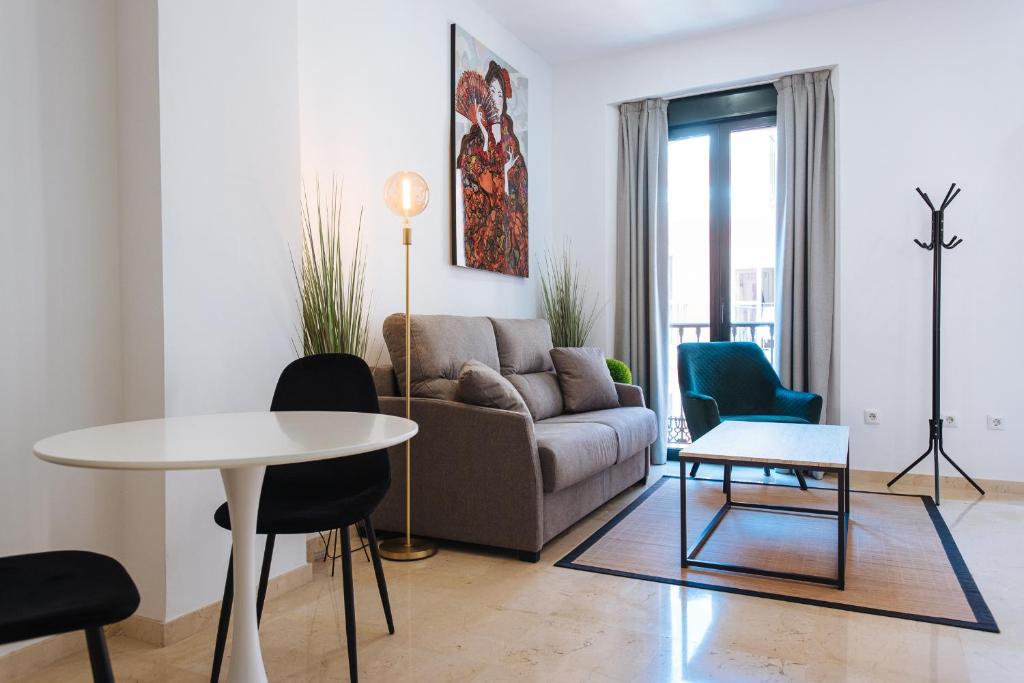 salon z kanapą, stołem i krzesłami w obiekcie Guardamino Dúplex Suite Apartment w Sewilli