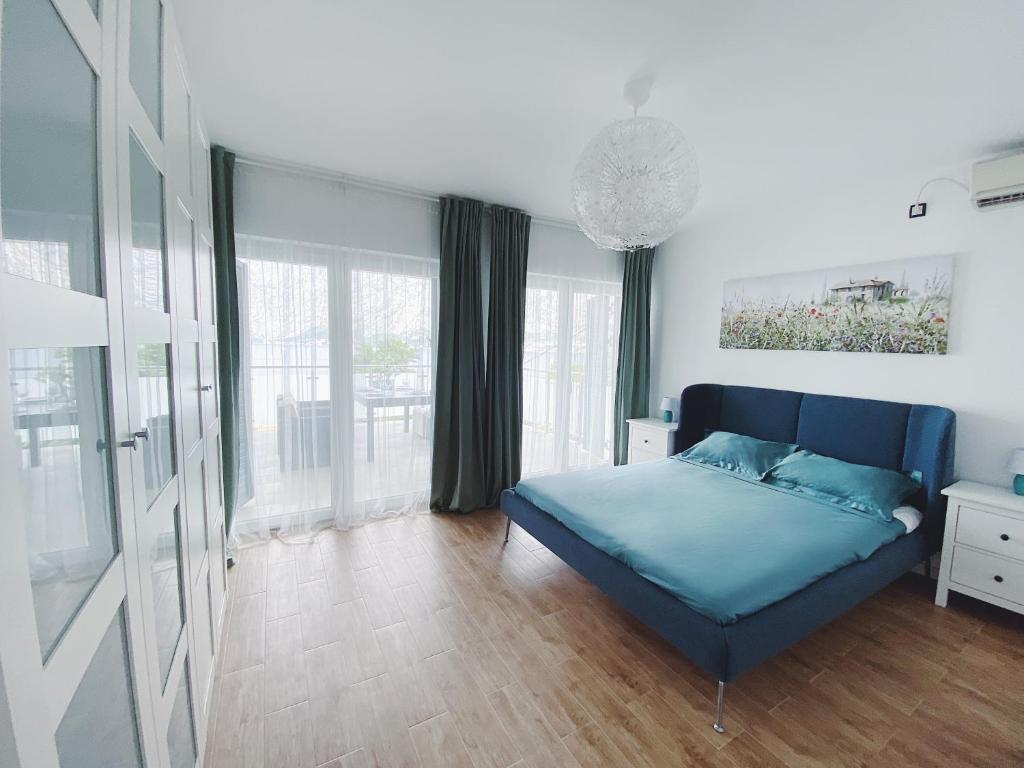 um quarto com uma cama azul num quarto com janelas em Amanito Apartments em Prcanj