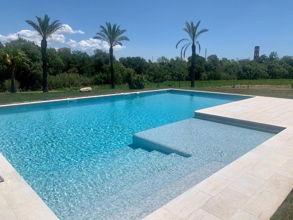 una piscina con agua azul y palmeras en Bio Resort Mediterráneo, en Sant Martí Sarroca
