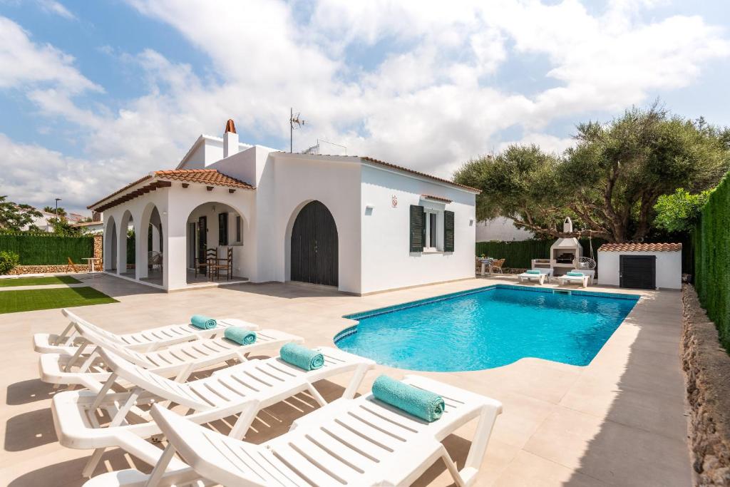 uma villa com uma piscina e espreguiçadeiras em Villa Menorca ROCAS by Mauter Villas em Cala'n Bosch