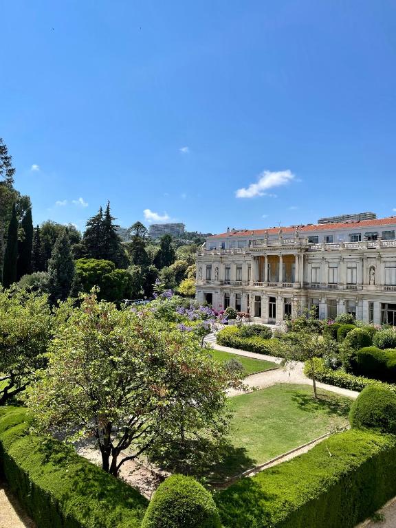 un grand bâtiment avec un jardin en face dans l'établissement Air-conditioned apartment with garage near the sea, à Nice