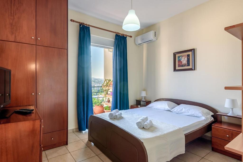 1 dormitorio con 1 cama con cortinas azules y ventana en Golden Beach Hill Apartments, en Kato Daratso