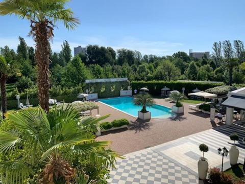 a courtyard with a swimming pool and palm trees at Savoia Hotel Regency in Bologna