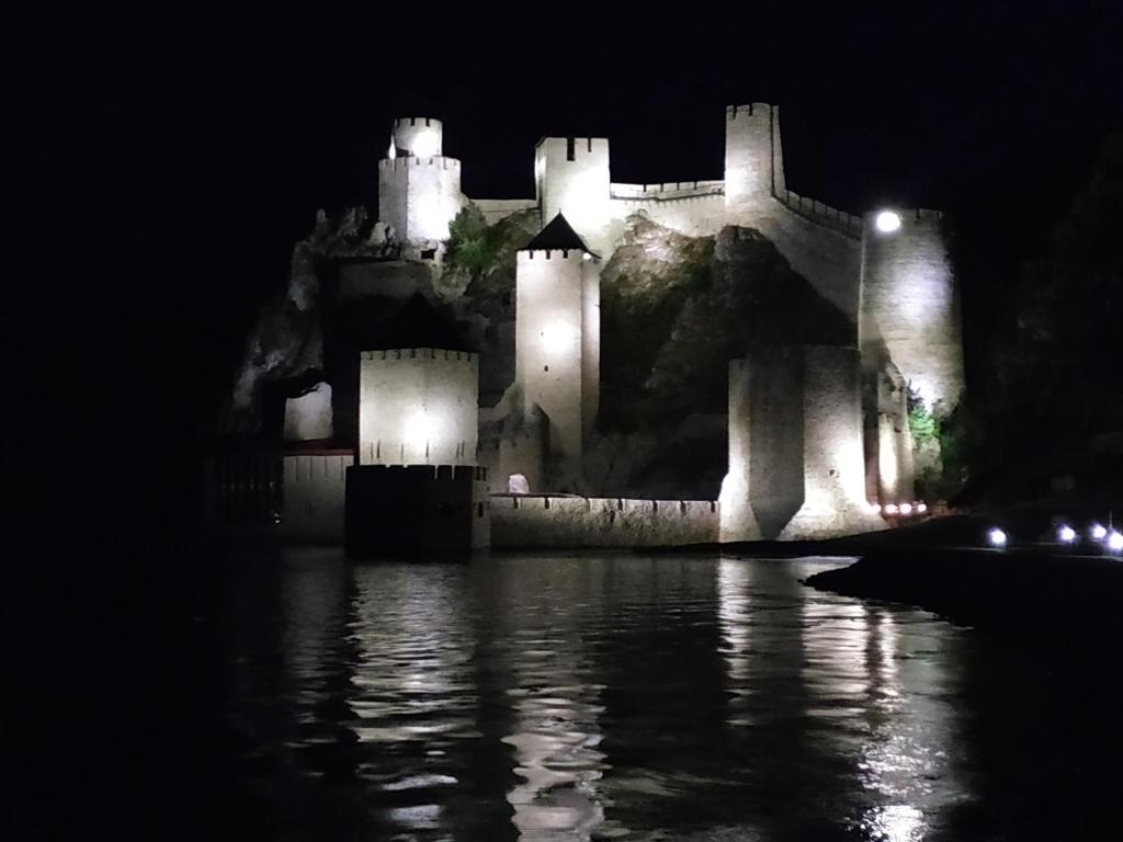 a castle lit up at night with water in front at STARA KOVAČNICA in Golubac