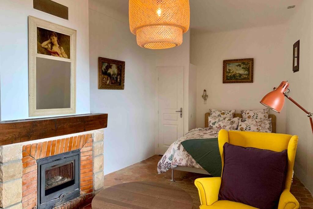 um quarto com uma cama, uma lareira e uma cadeira amarela em Confortable studio à Mons, au calme absolut em Mons