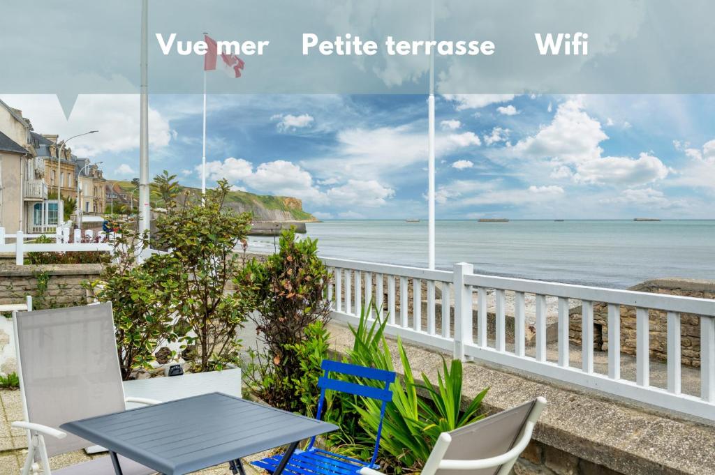 d'une table et de chaises sur un balcon donnant sur l'océan. dans l'établissement Appartement en front de mer avec terrasse et vue mer, à Arromanches-les-Bains