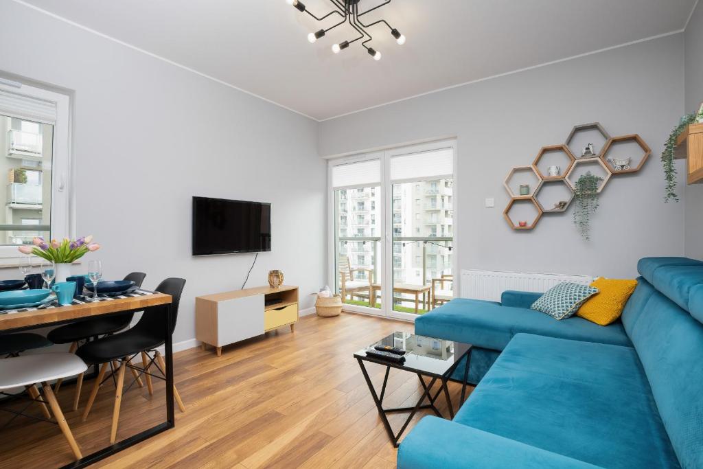 a living room with a blue couch and a table at Albatross Towers Przymorze Apartments by Renters in Gdańsk
