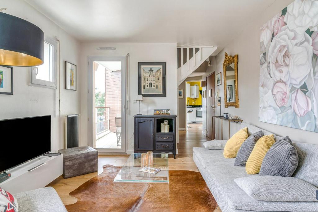 ein Wohnzimmer mit einem Sofa und einem TV in der Unterkunft NYMPHÉA - Duplex Hauts Pavés in Nantes