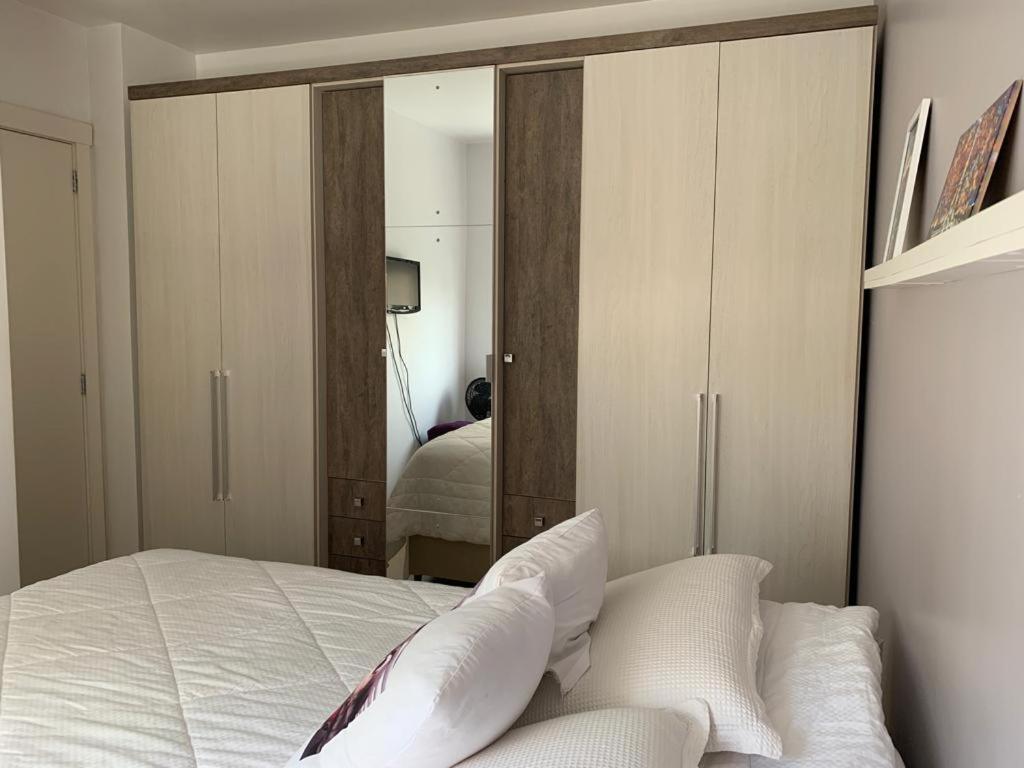 um quarto com uma cama branca e um espelho em Andy Apto Menino Deus/Cidade Baixa/Orla em Porto Alegre