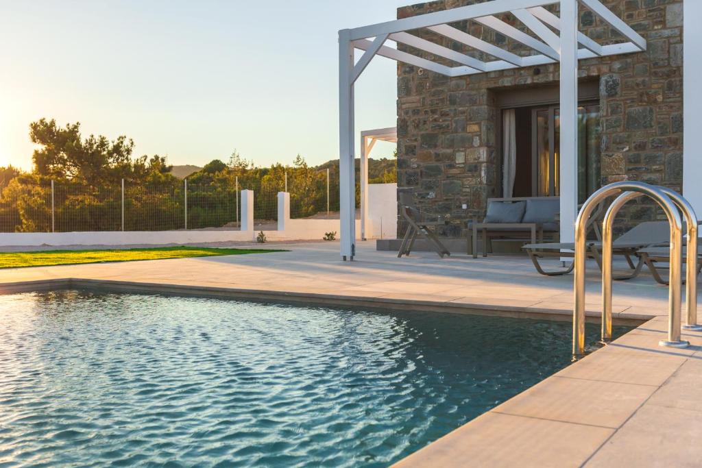 a swimming pool with a pergola next to a house at Kiotari Fresh in Kiotari