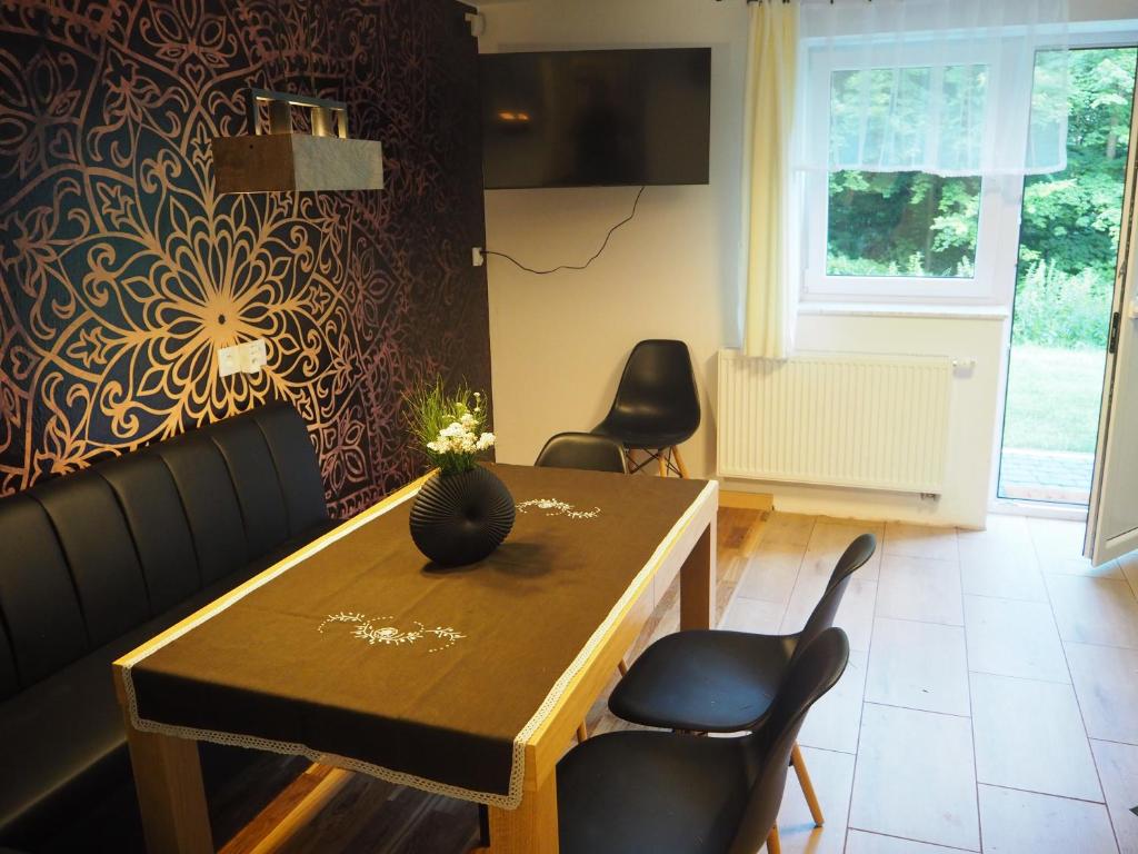 een woonkamer met een tafel en stoelen en een muur bij Komfortowy apartament z bezpośrednim wyjściem na ogród in Kalwaria Zebrzydowska