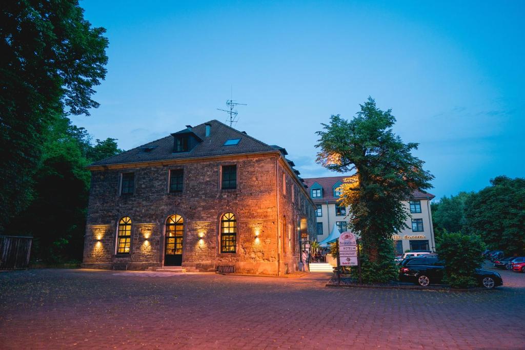 un viejo edificio de piedra en una calle con un árbol en Hotel Bachmühle, en Fulda