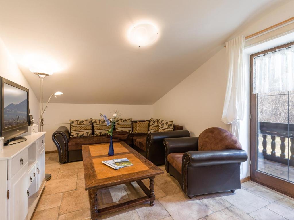 uma sala de estar com sofás, uma televisão e uma mesa em Bergschlössl - Appartment 25 mit Traumblick über das Inntal em Oberaudorf