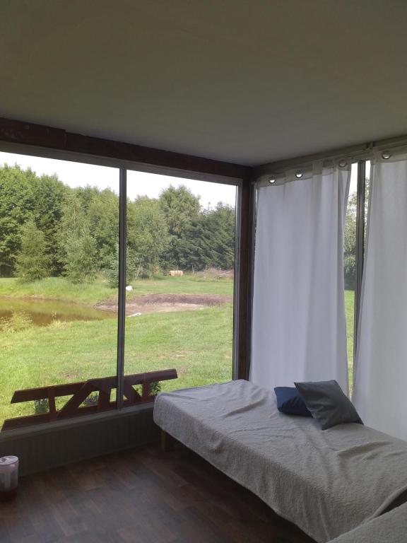 a bedroom with a bed and a large window at Domek letniskowy na Mazurach nad stawem in Gromoty