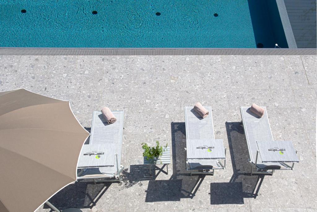 a group of white lounge chairs next to a swimming pool at Motel Peralba in Saronno