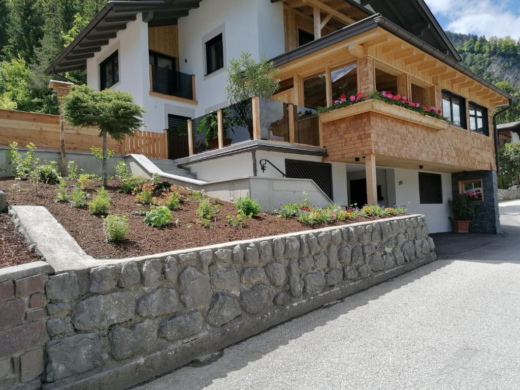 a house with a stone retaining wall in front of it at Apart Pichler in Schlitters