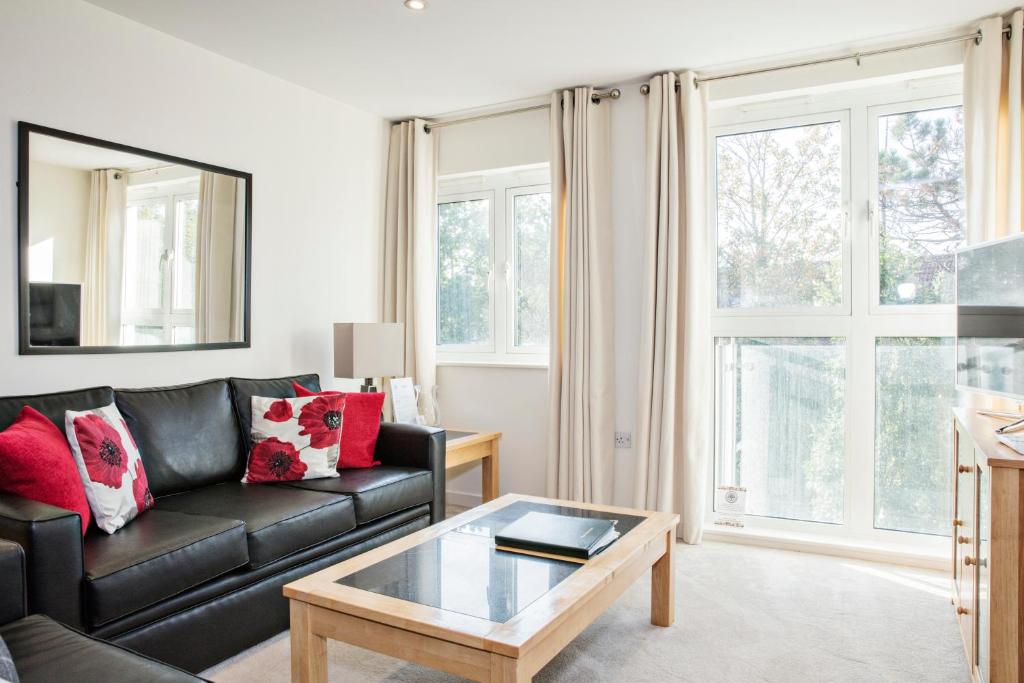 a living room with a black leather couch and a coffee table at Oakdale at Park Heights in Woking