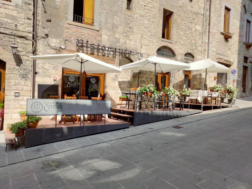 a patio area with tables, chairs and umbrellas at hotel dei consoli in Gubbio