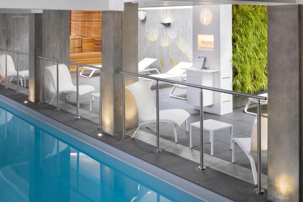 a swimming pool with a table and chairs next to a building at Terre de Provence Hôtel & Spa in Le Pontet