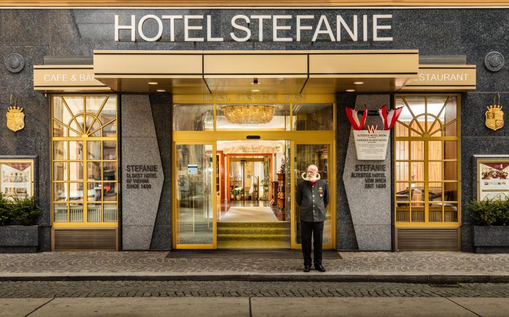 un hombre parado frente a una tienda de hotel en Hotel Stefanie - VIENNA'S OLDEST HOTEL en Viena