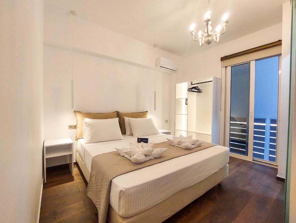 a white bedroom with a large bed and a window at Polymnia Luxury Apartments Argostoli in Argostoli
