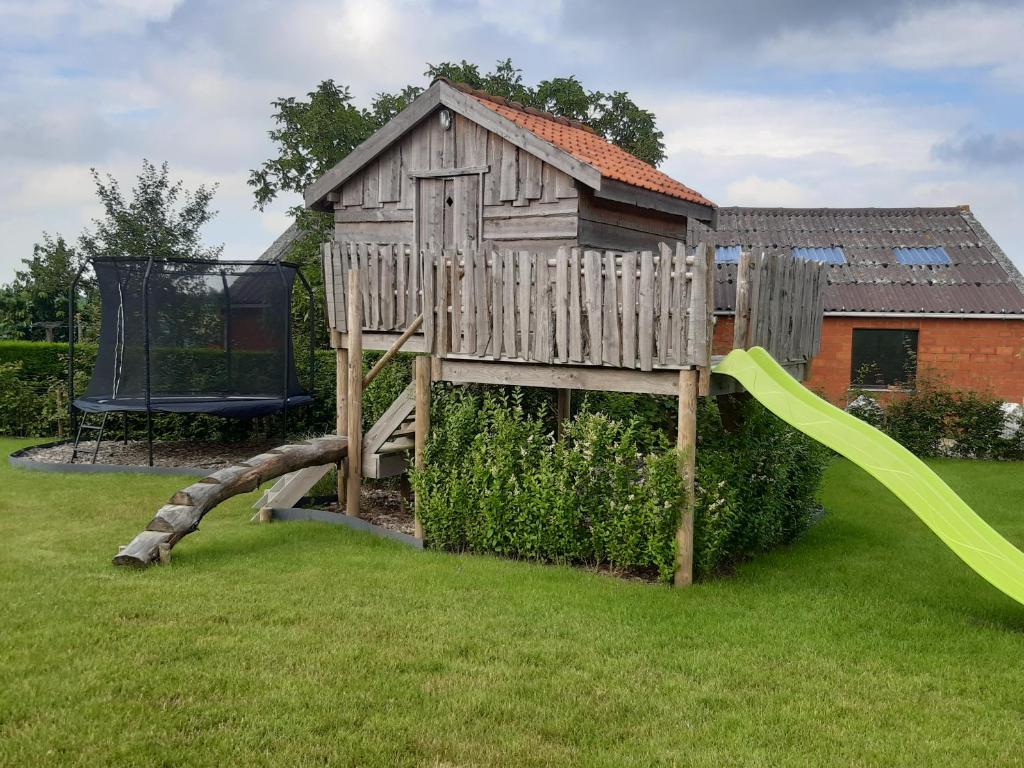 uma estrutura de jogos de madeira num quintal com um parque infantil em vakantiehuis zoetendaal em Reningelst