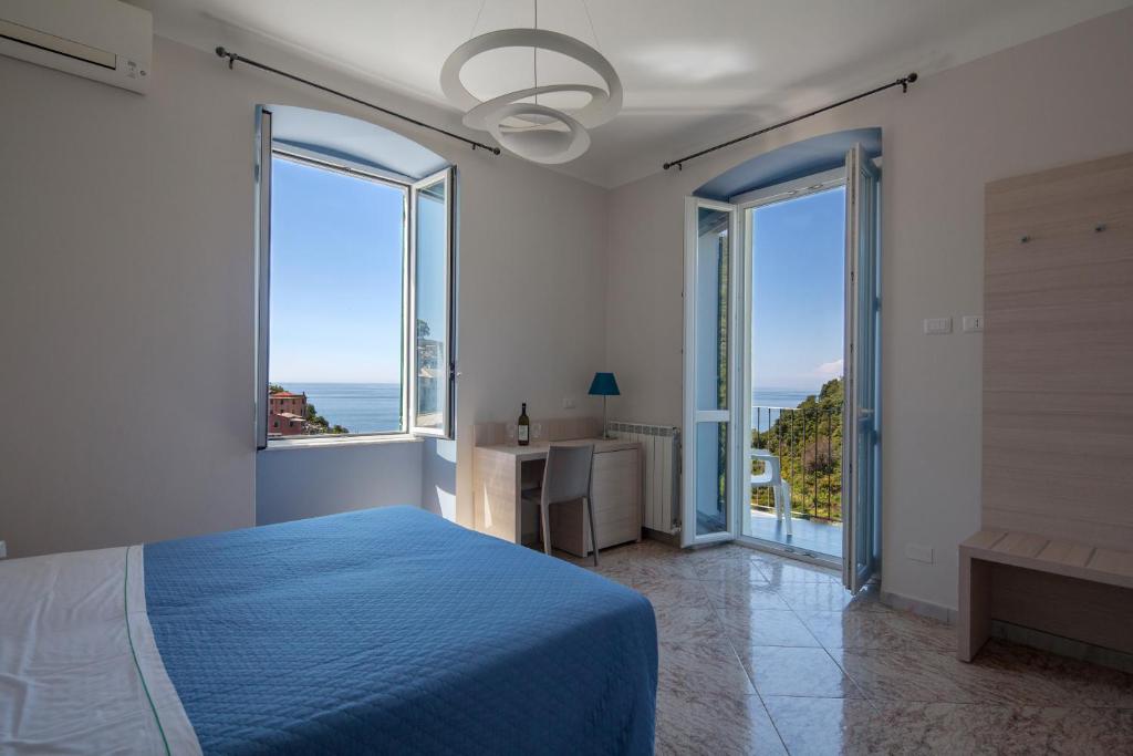 - une chambre avec un lit bleu et de grandes fenêtres dans l'établissement Cecio 5 Terre Rooms, à Corniglia